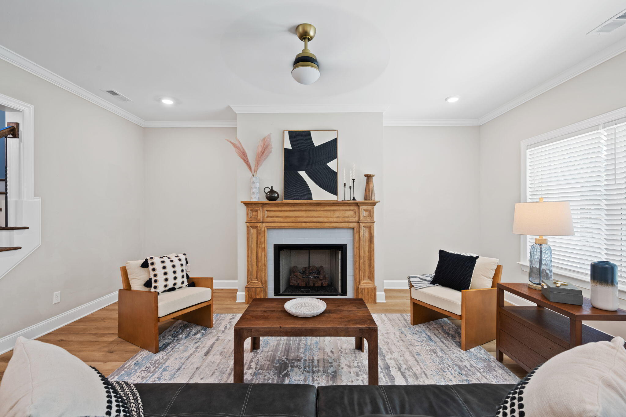 Living room with a wood-mantel fireplace, paired armchairs, and a patterned area rug.