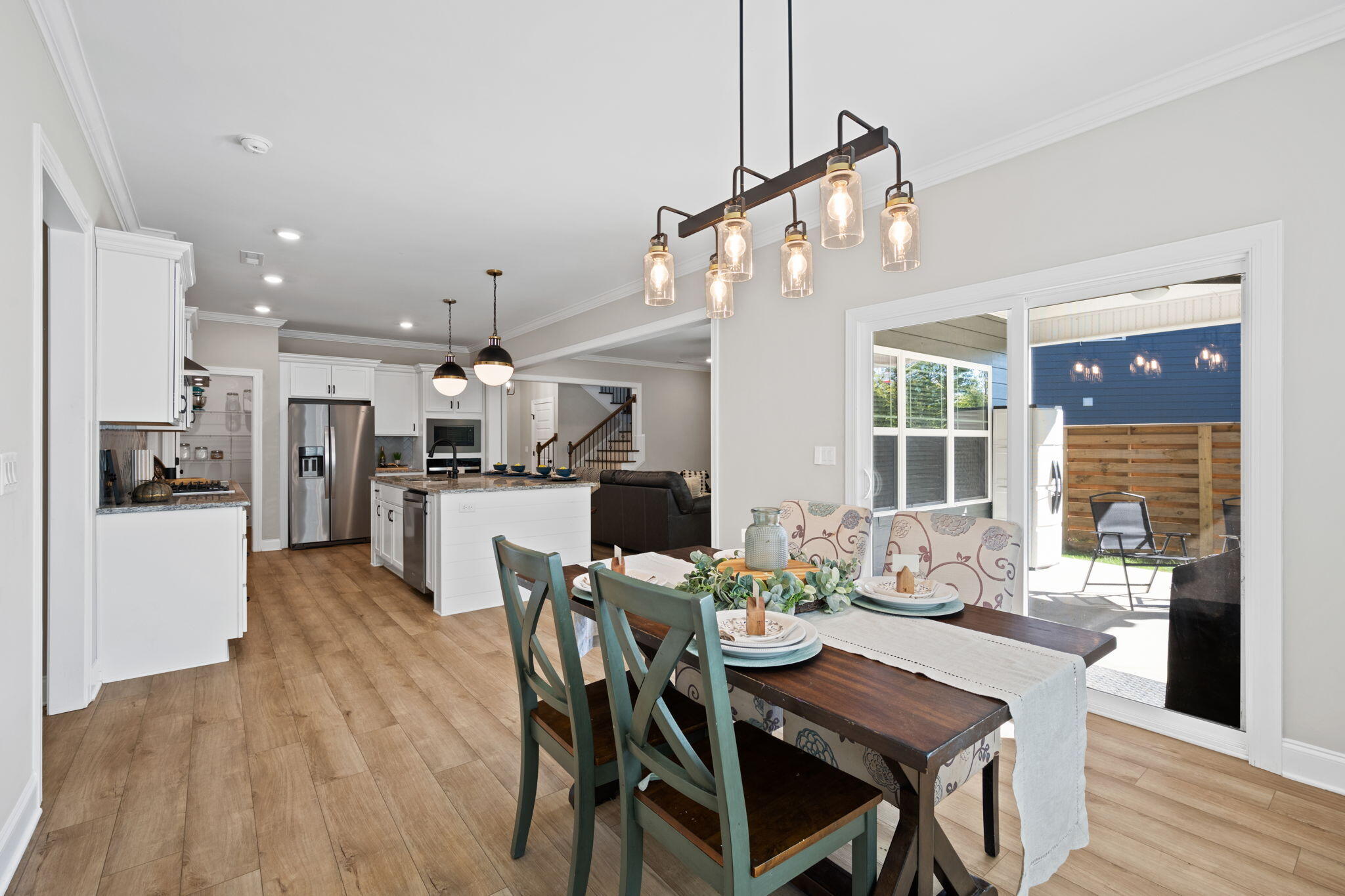 Open-plan kitchen and dining area with a large island, set dining table, and sliding doors to the patio.