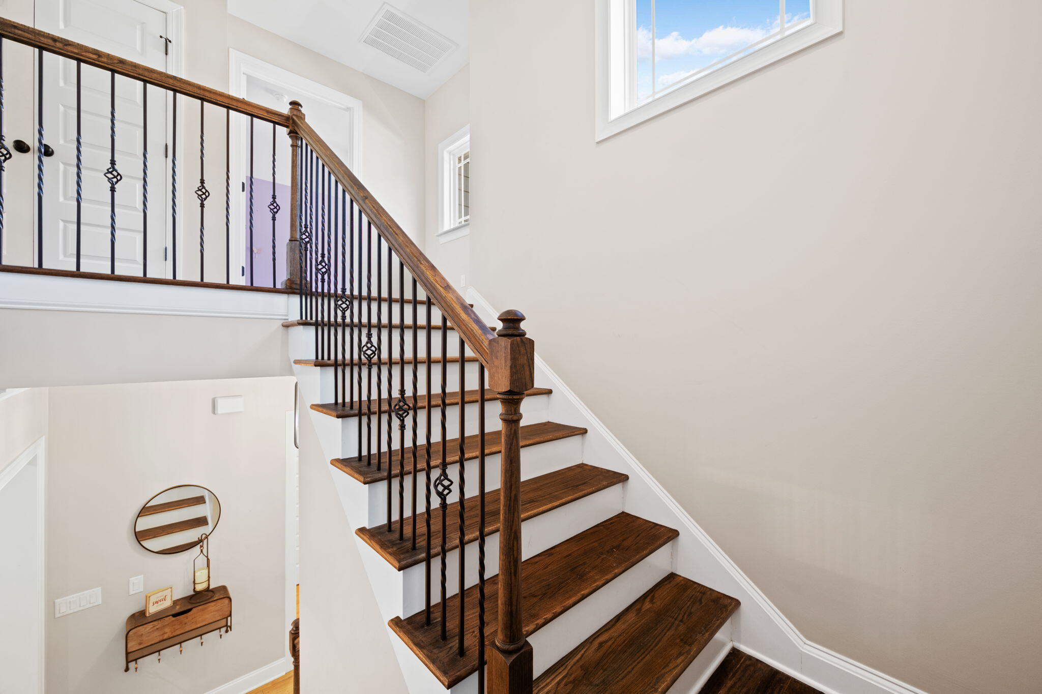 Interior staircase with dark wood treads, white risers, and ornate black iron balusters.