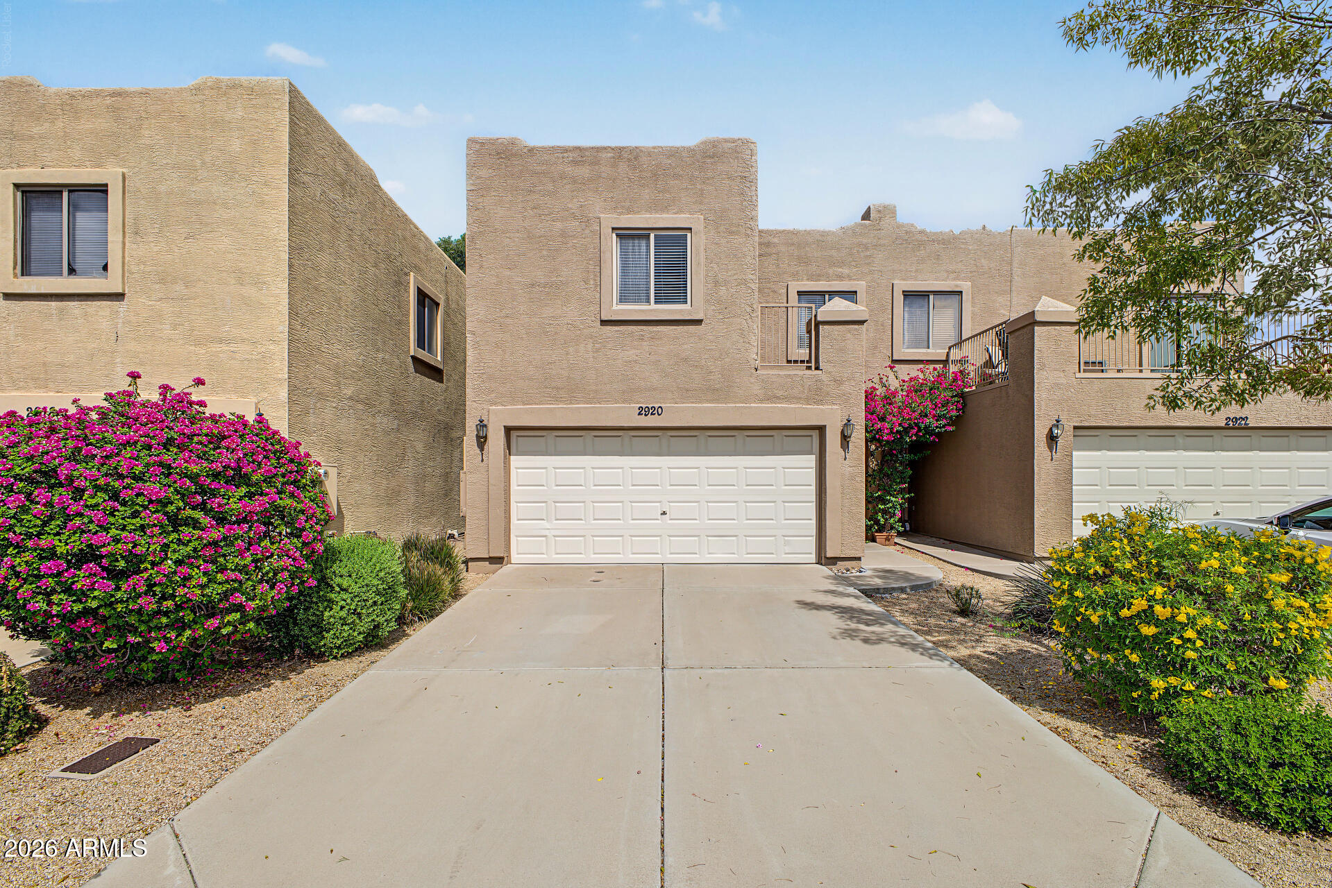 Front exterior of 2920 E Eberle Lane with a two-car garage and flowering shrubs.