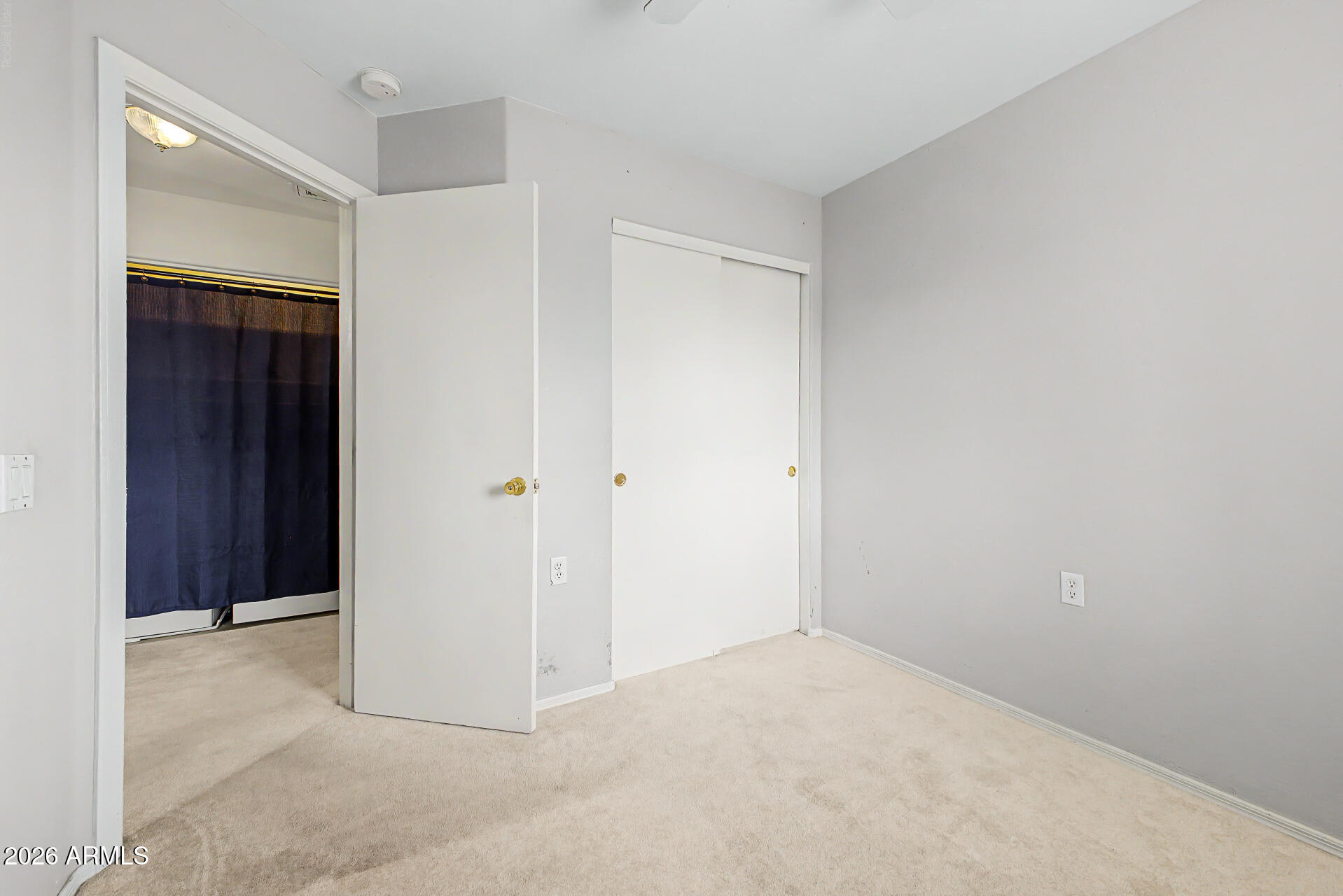 Empty carpeted room with a sliding closet door and an open doorway to a bathroom.