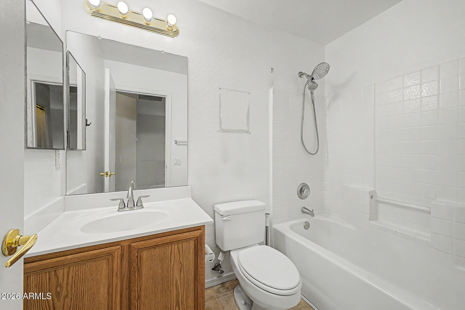Bathroom with a wood vanity, mirrored medicine cabinet, and white tub-shower.