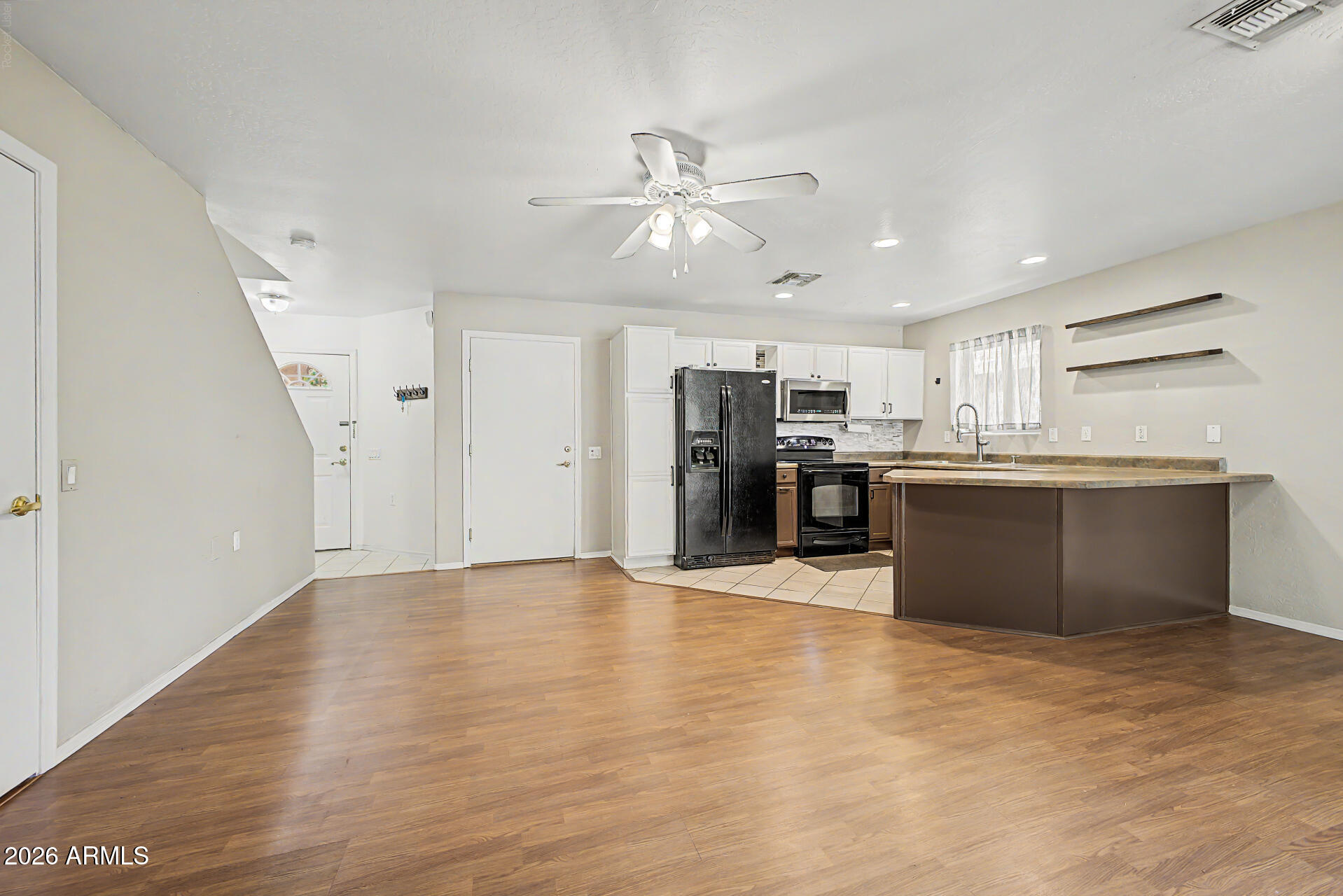 Open kitchen and dining area with wood floors, white cabinets, and a peninsula.