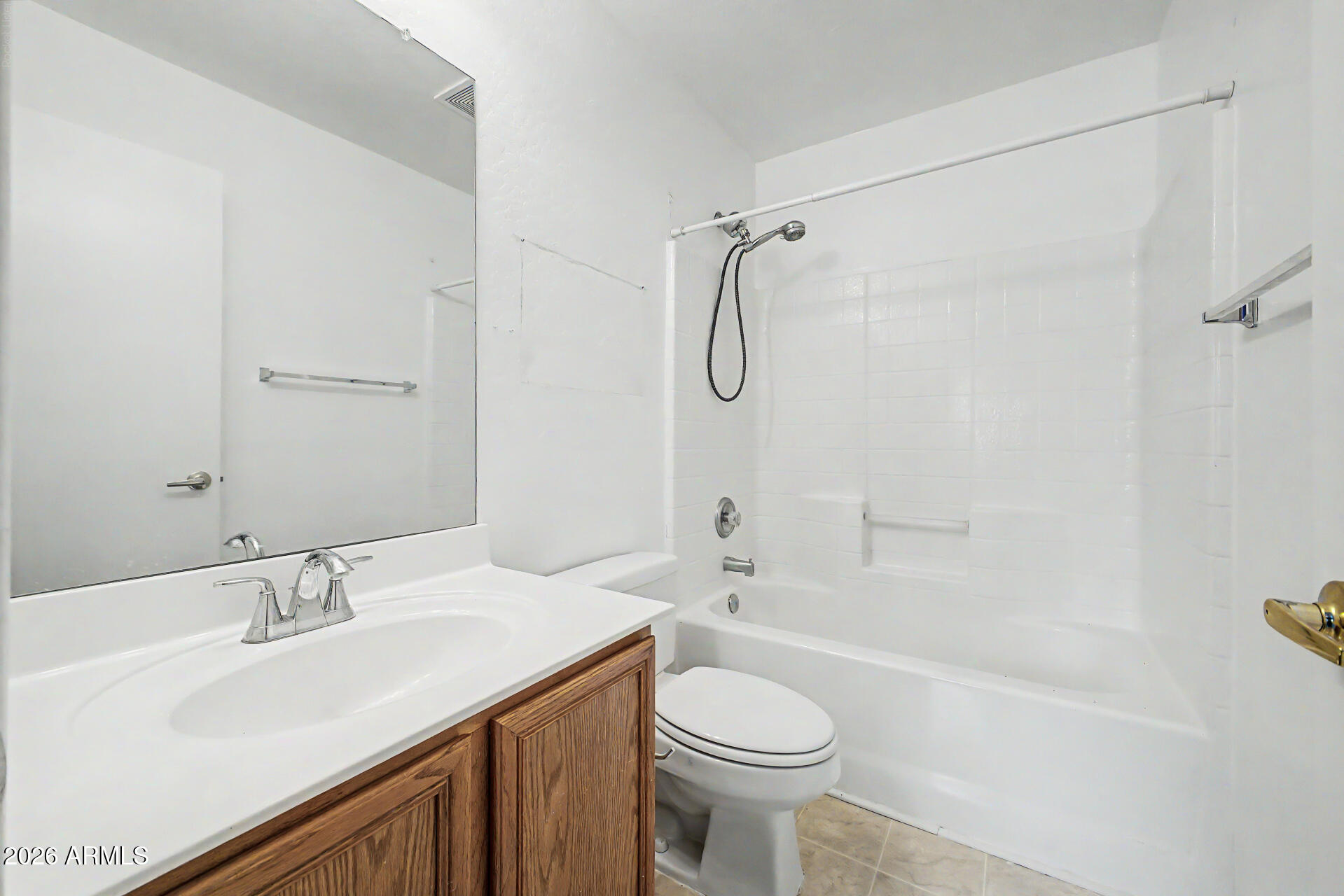 Bathroom with a white tub and shower, large mirror, and wood vanity.