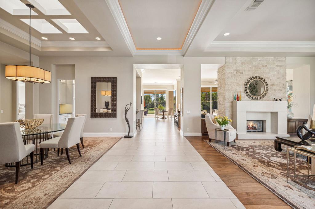 Open-plan living and dining room with a stone fireplace and coffered ceiling