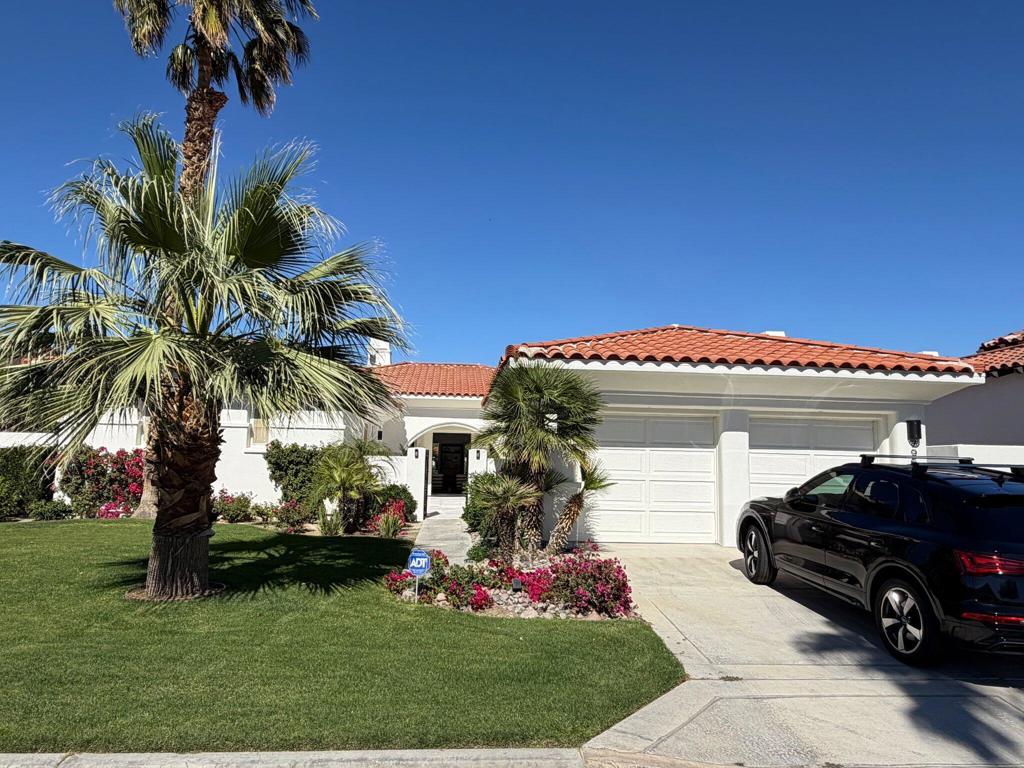 White stucco home with red tile roof, palm trees, and attached double garage.