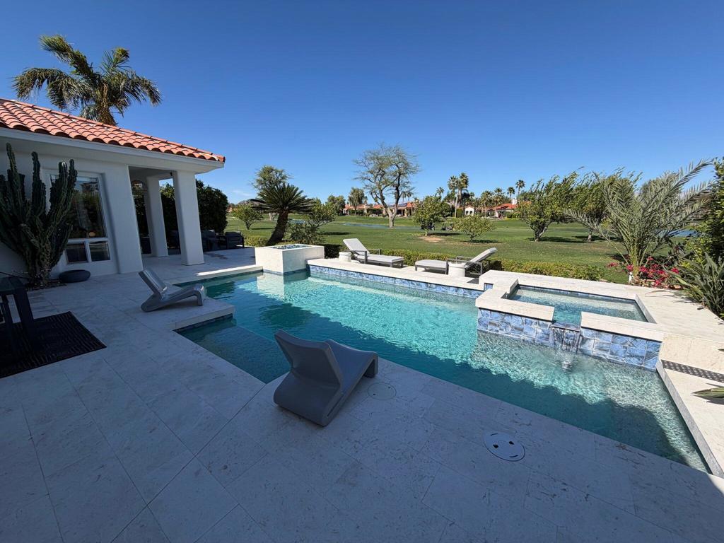 Backyard pool with raised spa, lounge chairs, and a manicured golf course beyond.