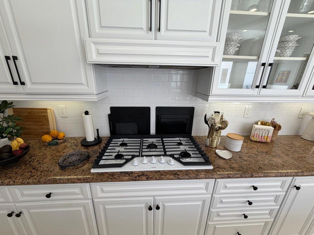 Kitchen with a gas cooktop, granite counters, and white cabinetry.