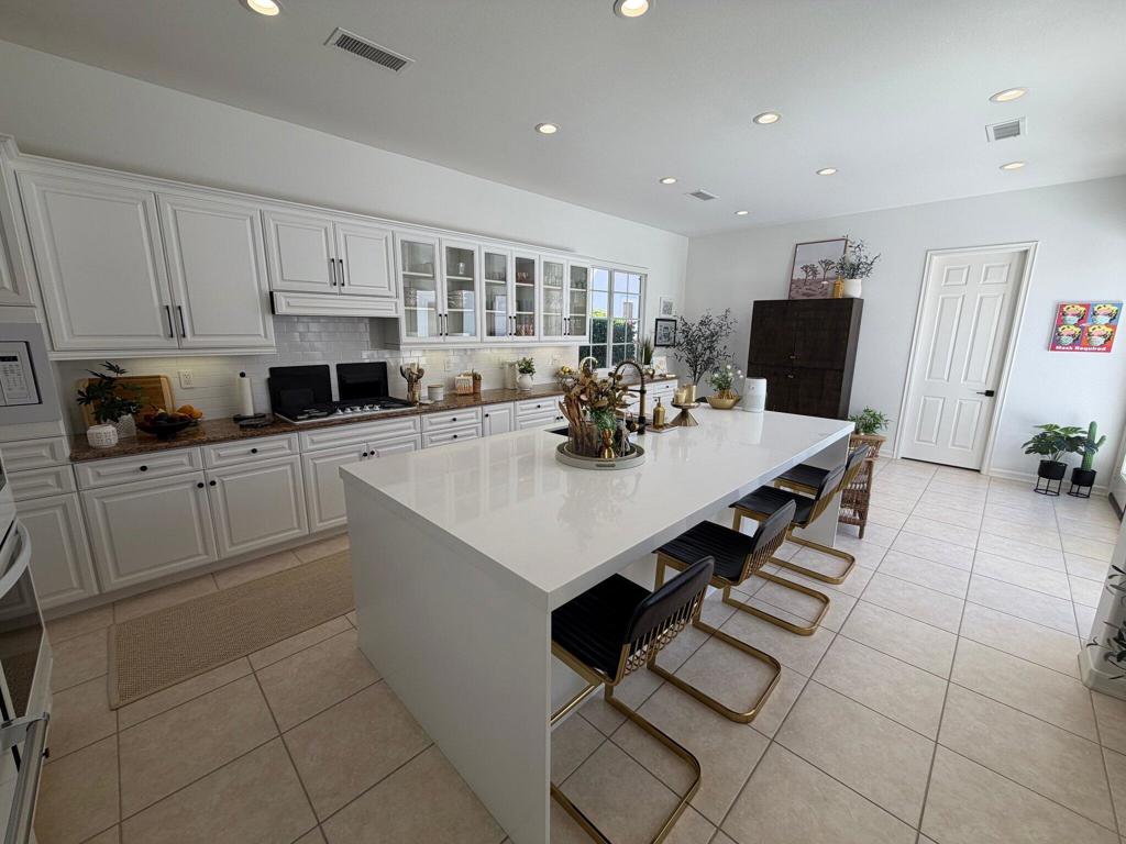 Bright kitchen with a large white island, seating, and extensive cabinetry.