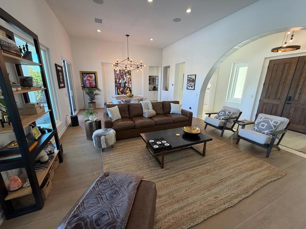Living room with a brown sofa, woven rug, and arched opening to the entryway.