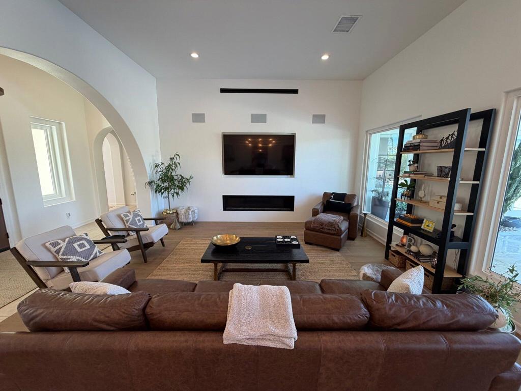 Furnished living room with a wall-mounted television, linear fireplace, and seating around a coffee table.