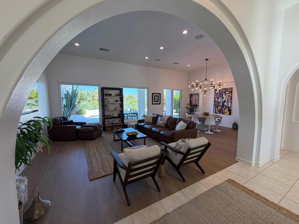 Living room with dark leather seating and a dining area beneath a large arched opening.