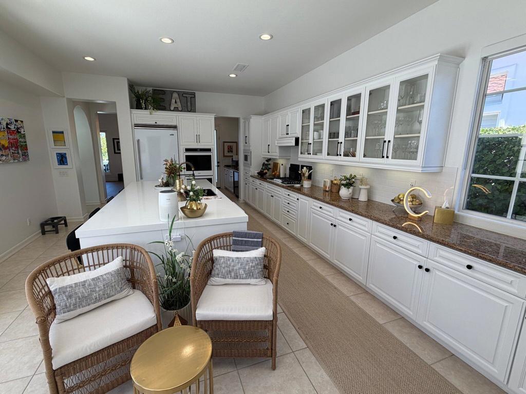 Bright kitchen with white cabinetry, a large island, glass-front cabinets, and a built-in double oven.