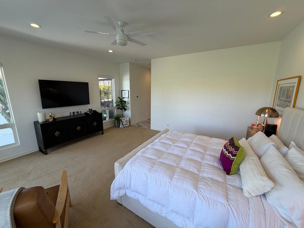 Bedroom with a white bed, ceiling fan, and black media console.