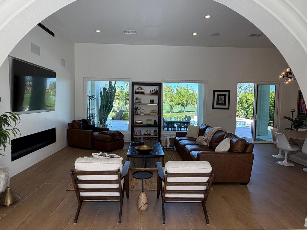 Living room with leather seating, a fireplace, and windows overlooking a landscaped outdoor area.
