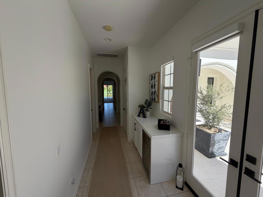 Bright entry hallway with a console cabinet, glass patio door, and arched doorway.
