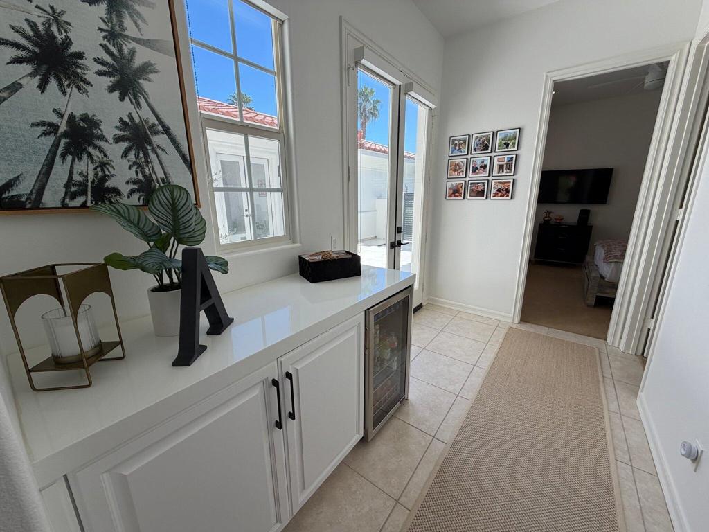Bright hallway with white built-in cabinetry, a beverage refrigerator, and a doorway to a bedroom.