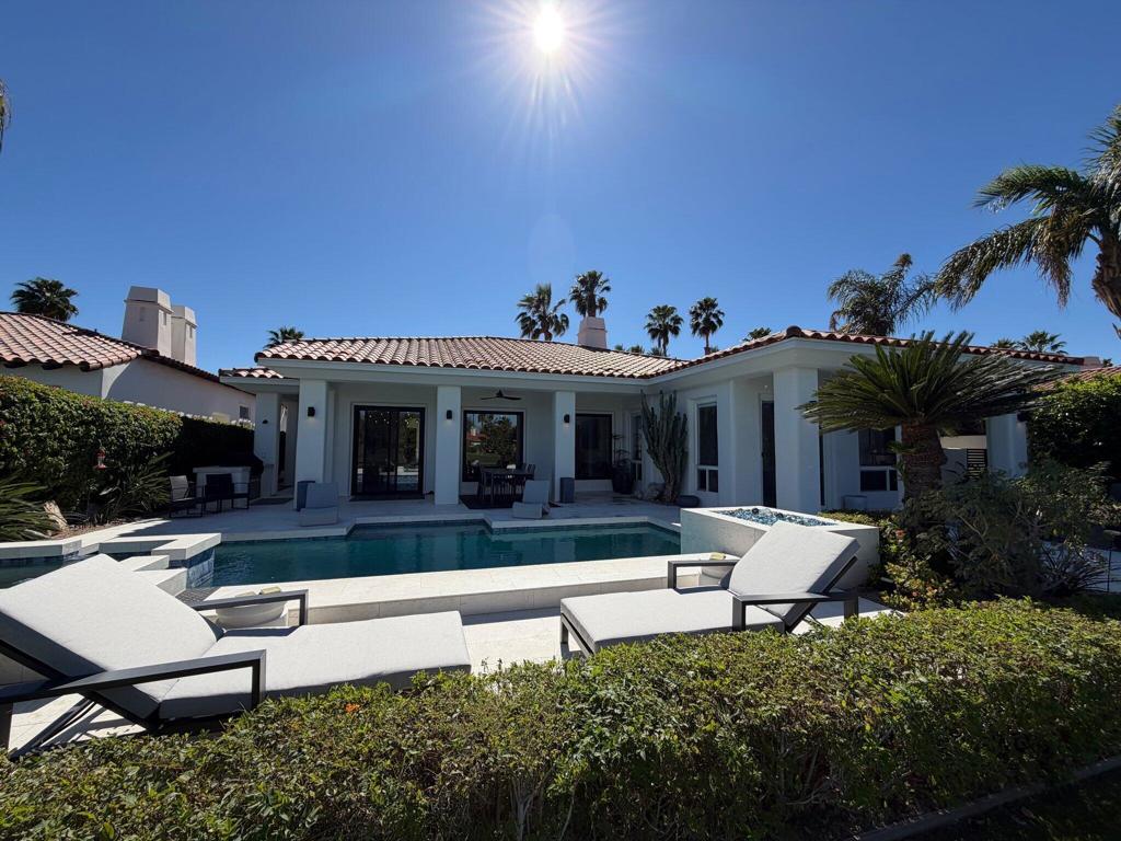 La Quinta home with a swimming pool, tiled roof, and white lounge chairs in the sunny backyard.