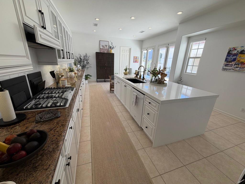 Bright kitchen with a large white island, gas cooktop, and granite countertops.