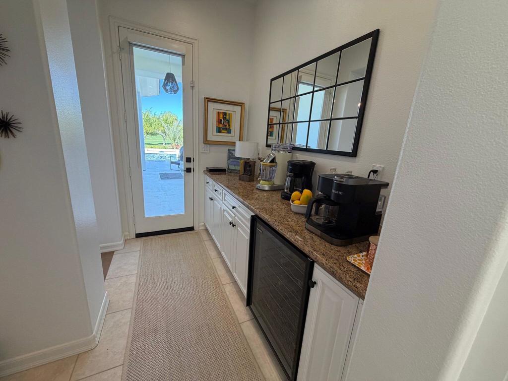 Beverage bar with a granite counter, coffee makers, and a glass door opening to the patio.