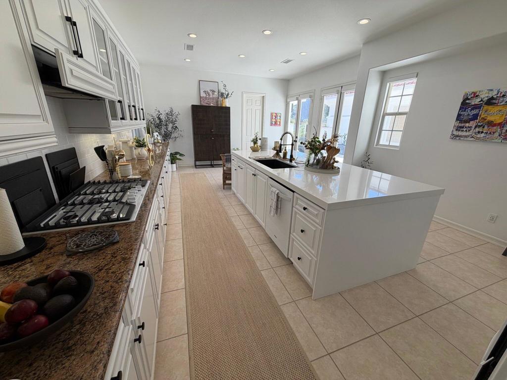 Bright kitchen with a large white island, gas cooktop, and windows overlooking the outdoors.