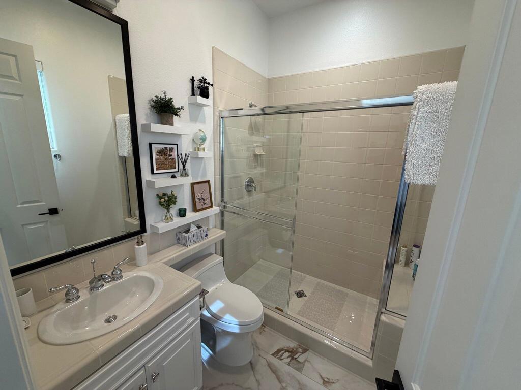 Bathroom with a white vanity, toilet, and glass-enclosed tub and shower.