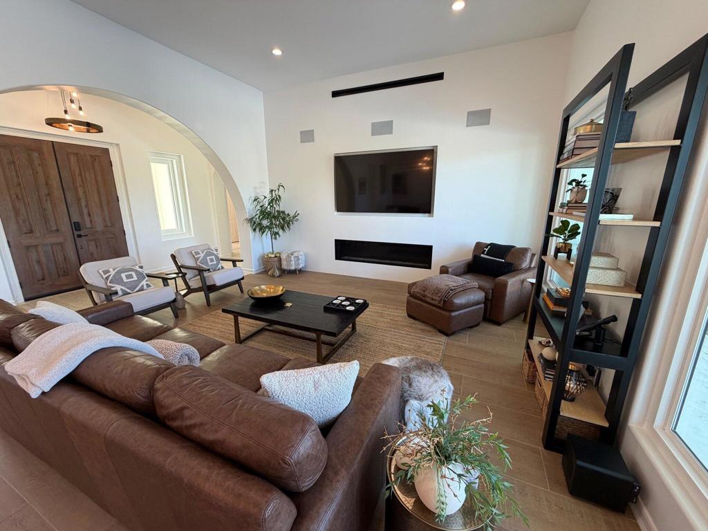 Living room with brown leather seating, a wall-mounted television, and a black shelving unit.