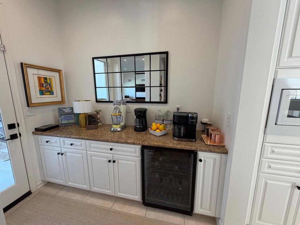 Built-in wet bar with a beverage refrigerator, coffee makers, and a large grid mirror.