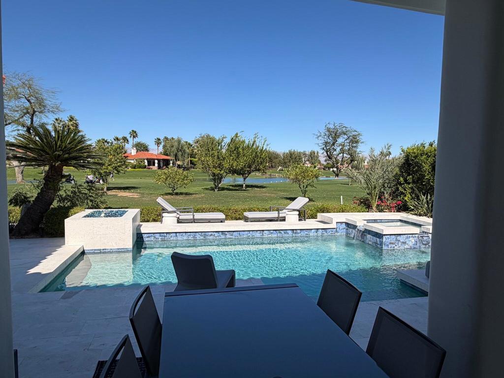 Backyard pool and patio dining area overlooking a golf course and water.