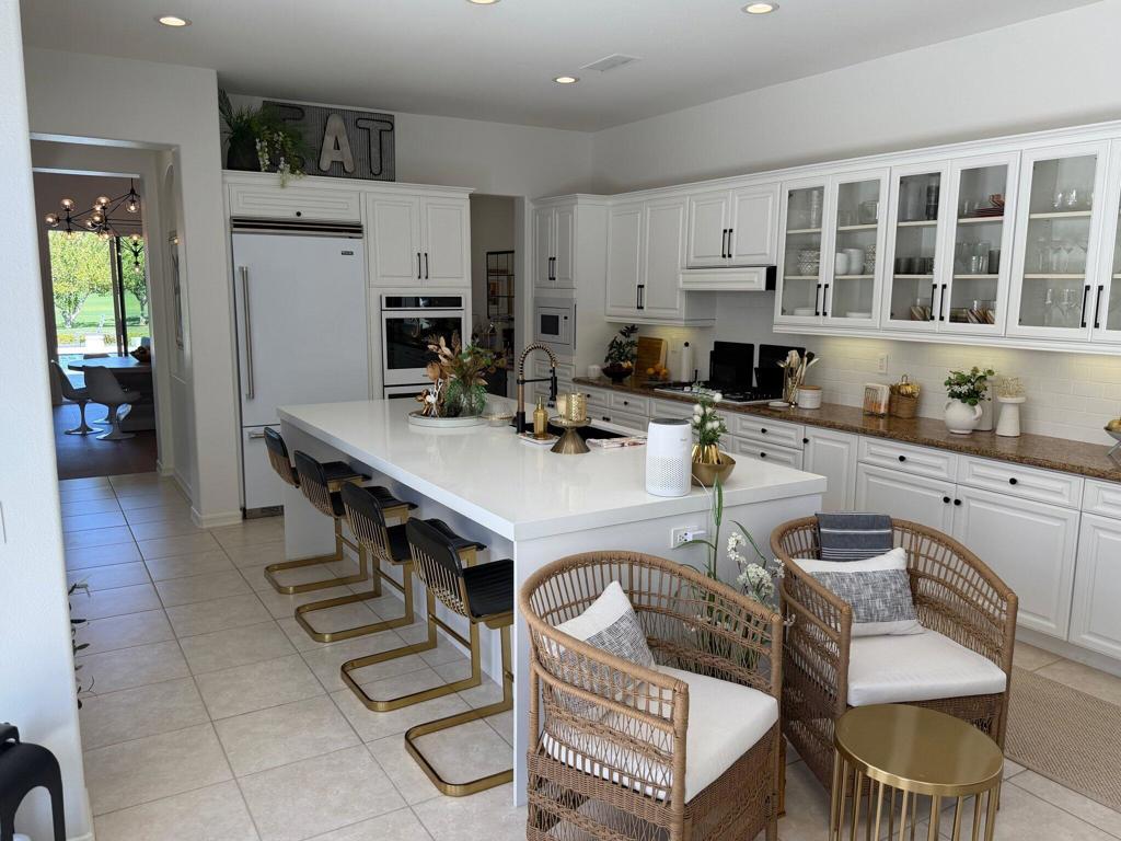 Kitchen with a large white island, bar seating, and wicker chairs.