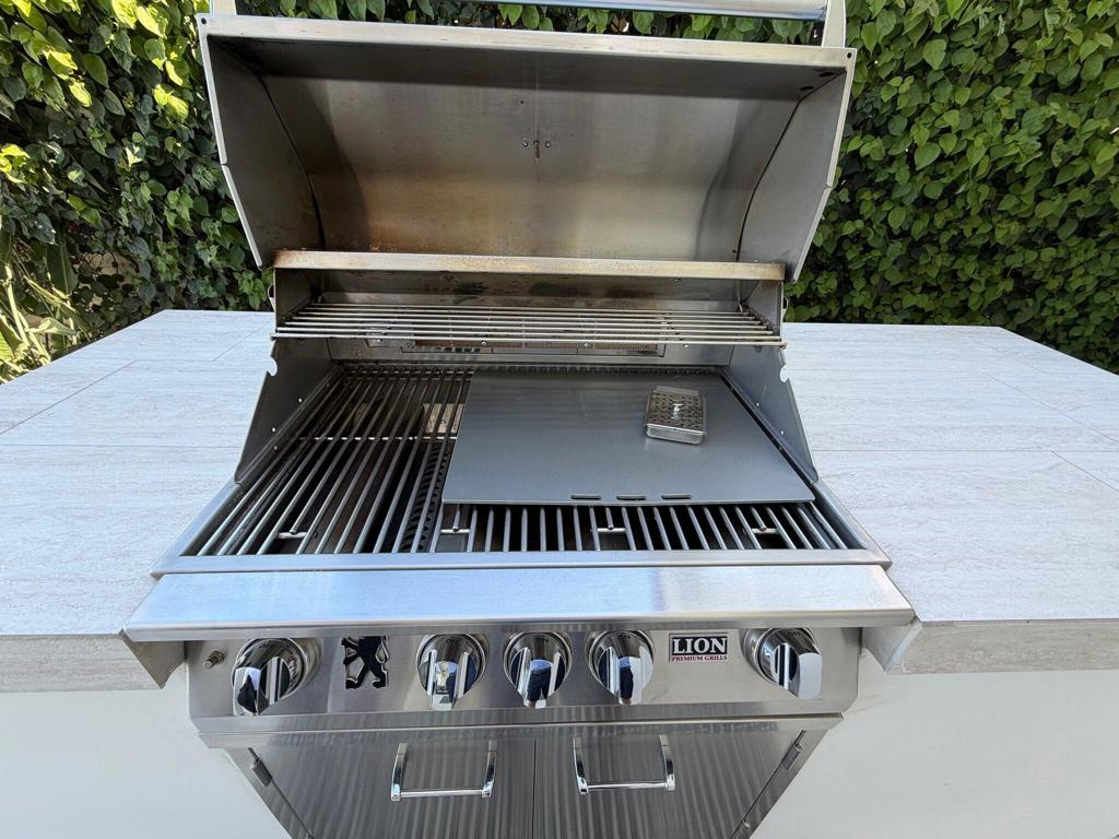 Built-in stainless steel grill with open lid and side counters.
