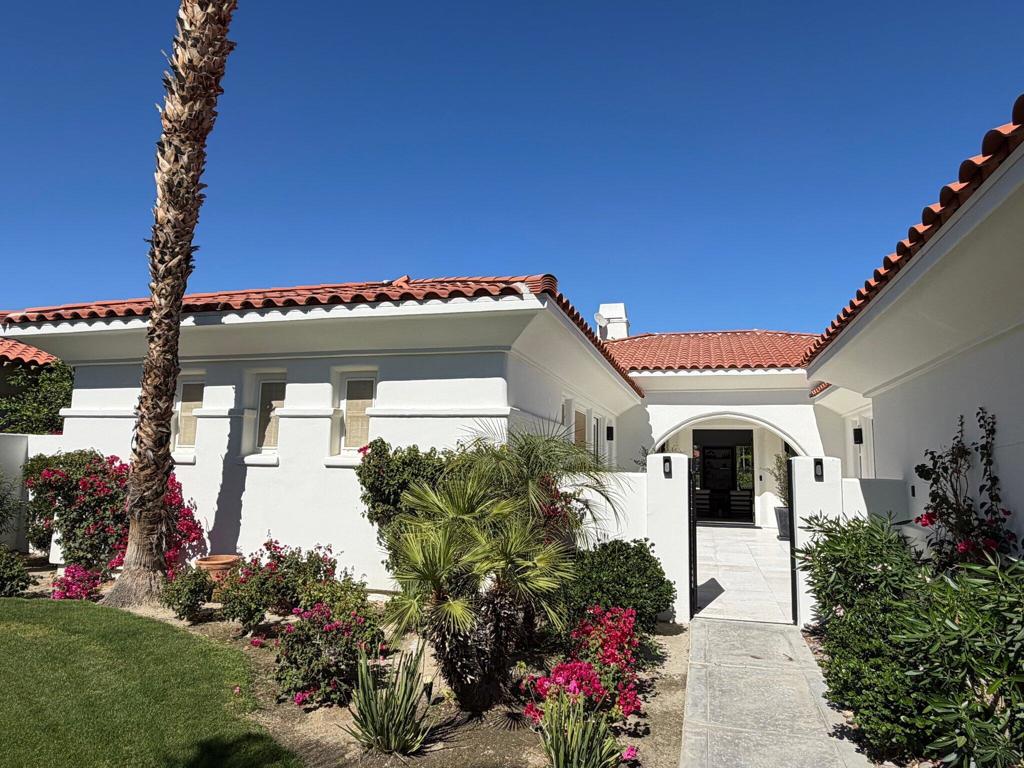 White stucco home with red tile roof, arched entry, and landscaped walkway.
