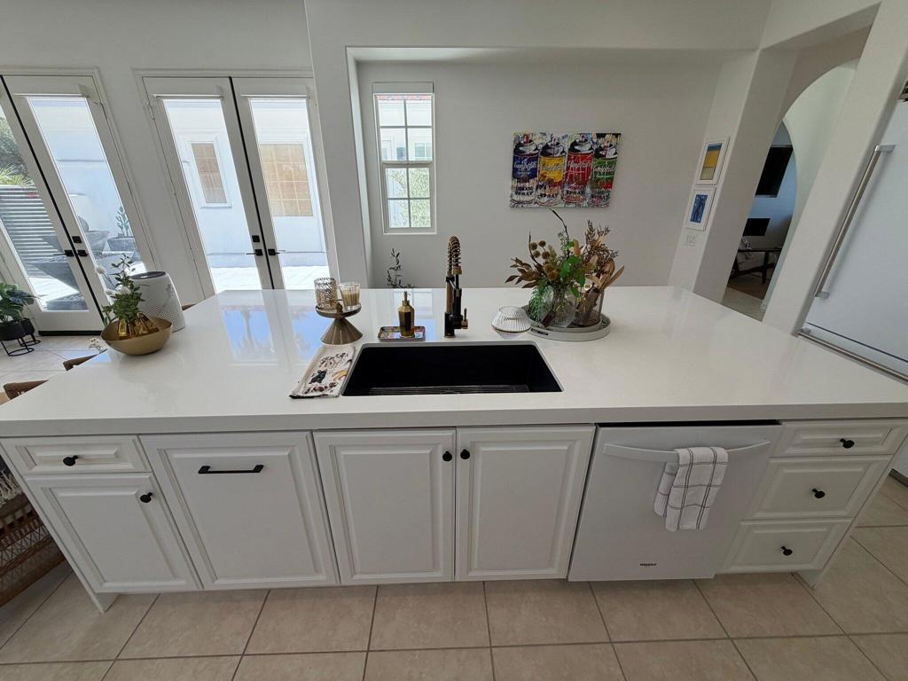 Kitchen island with a black sink, white cabinetry, and glass doors opening to a patio.