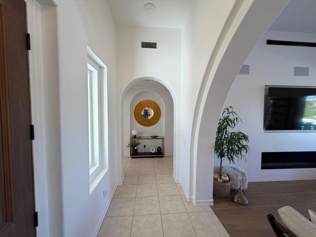 Tiled entry hallway with arched alcove, console table, and view into a living room with a fireplace.
