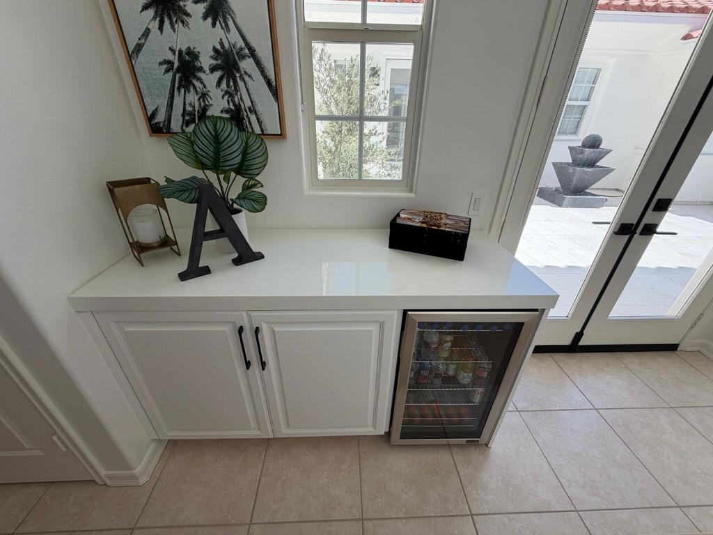 Built-in bar cabinet with a glass-front beverage refrigerator beside doors to the patio.