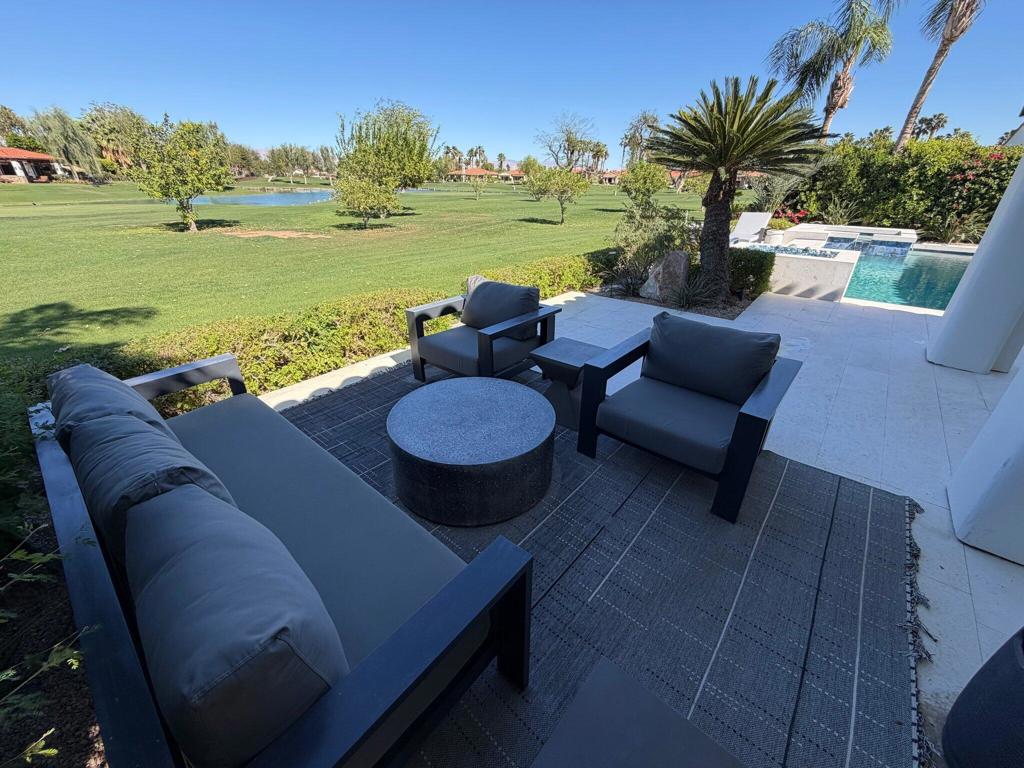 Furnished patio with lounge seating overlooking a pool and landscaped golf course.