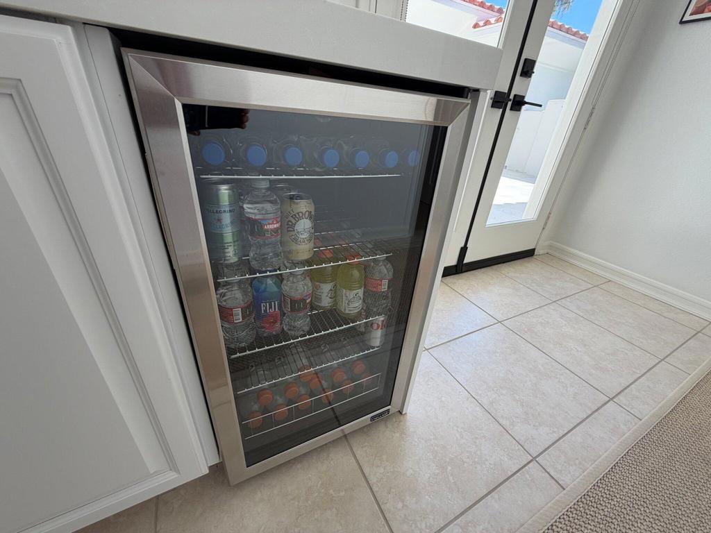 Built-in glass-front beverage refrigerator stocked with drinks beside a glass exterior door.