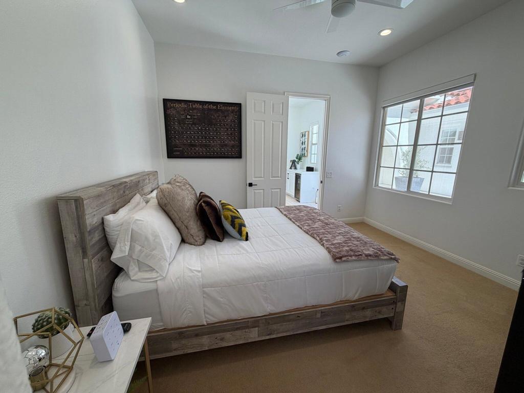 Bedroom with a wood-framed bed, periodic table wall art, and a large window.