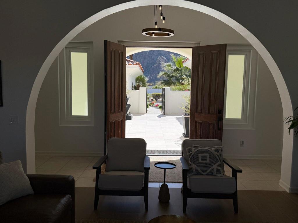 Furnished living room looking through open double doors toward a mountain view.