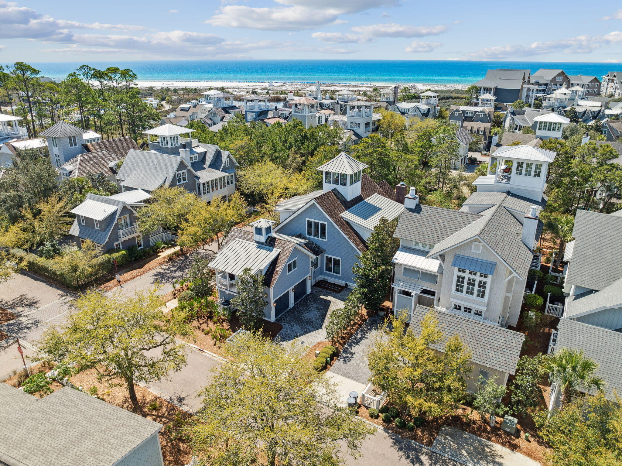 Aerial view of coastal homes with a sandy beach and turquoise ocean beyond.