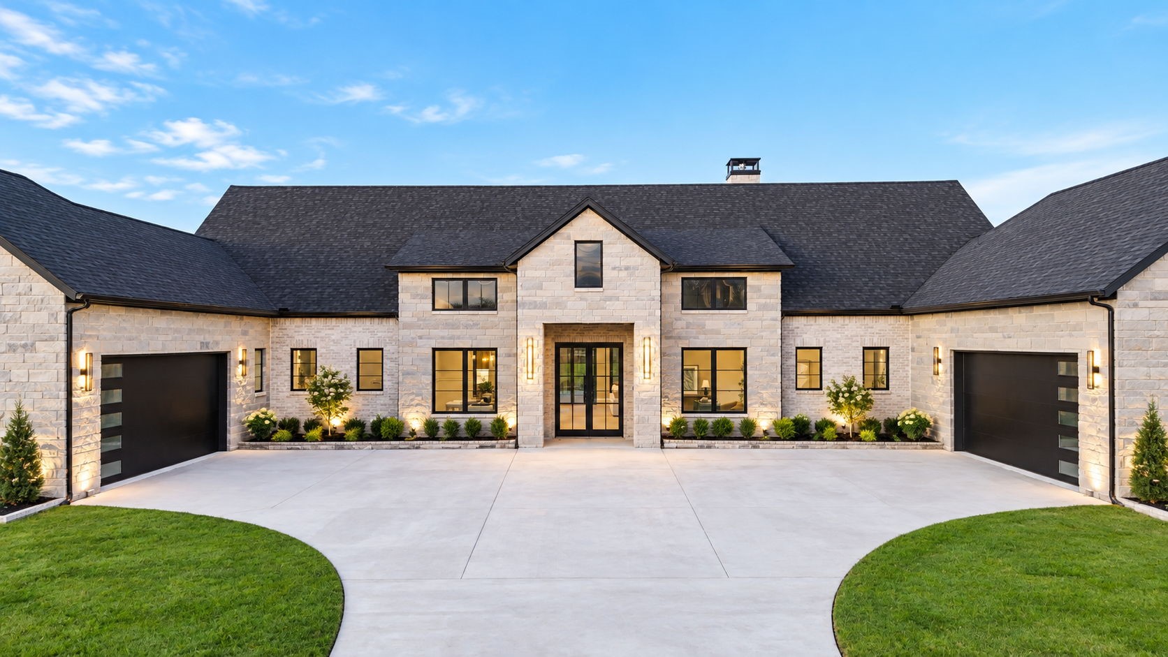 Stone house with a central entry, two garages, broad driveway, and landscaped lawn.