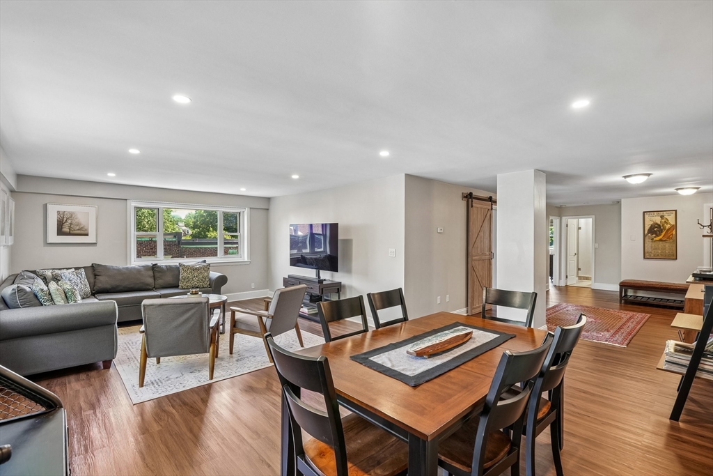 Open-plan living and dining area with a wooden table, gray sectional, and sliding barn door.
