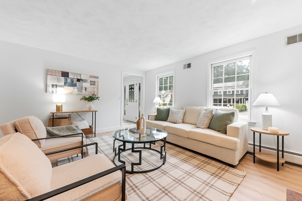 Staged living room with cream seating, a round glass coffee table, and large windows.
