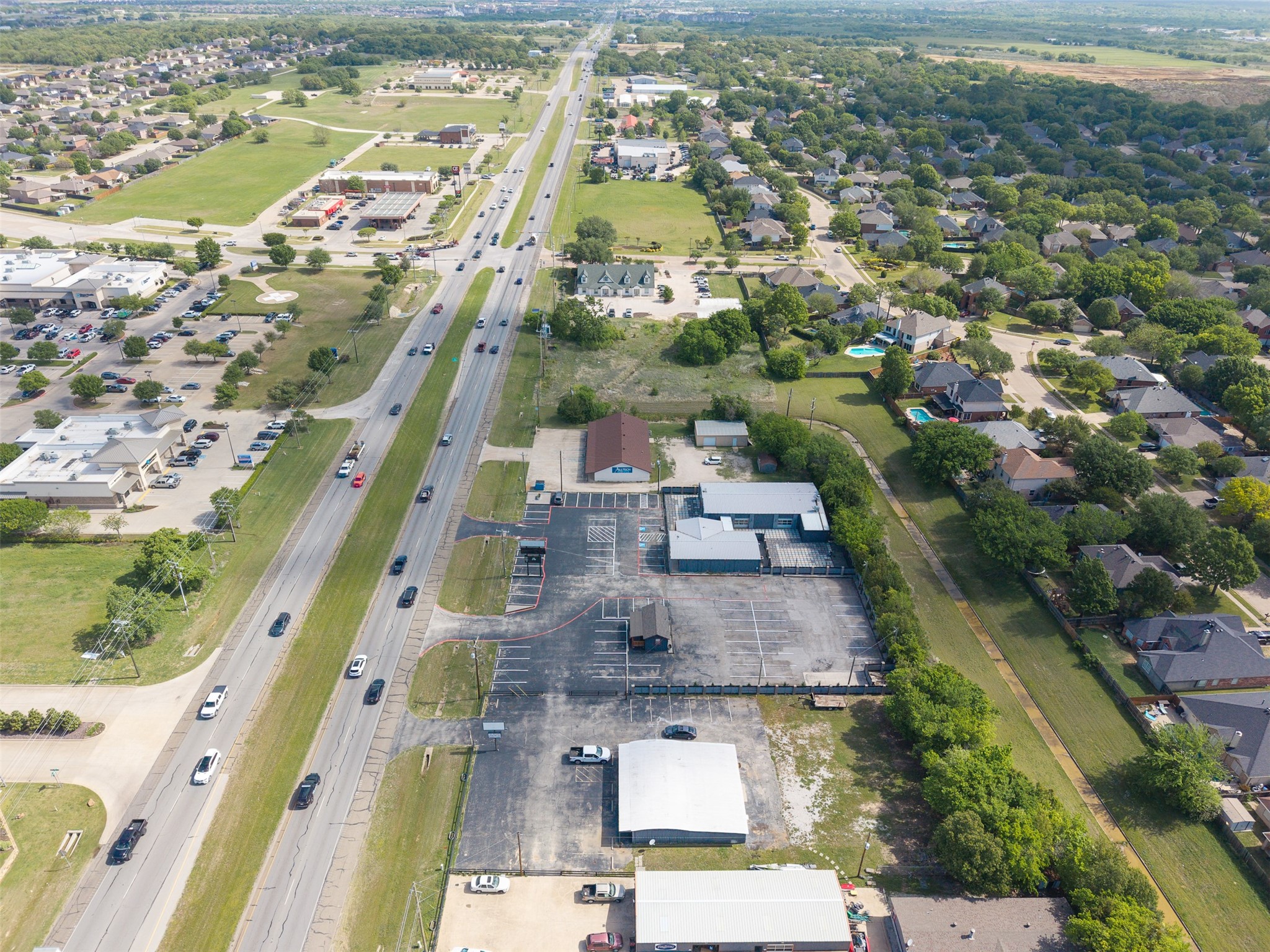 Aerial view of a commercial property and parking lot beside a busy road.