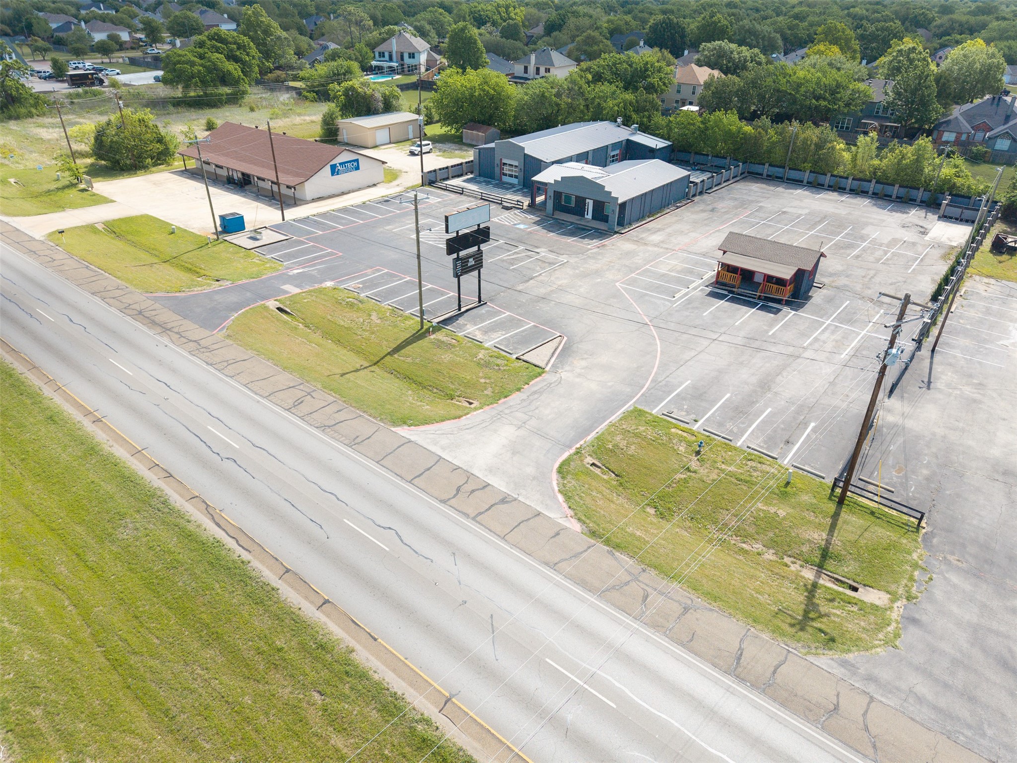Aerial view of commercial buildings and a broad parking lot beside a road.