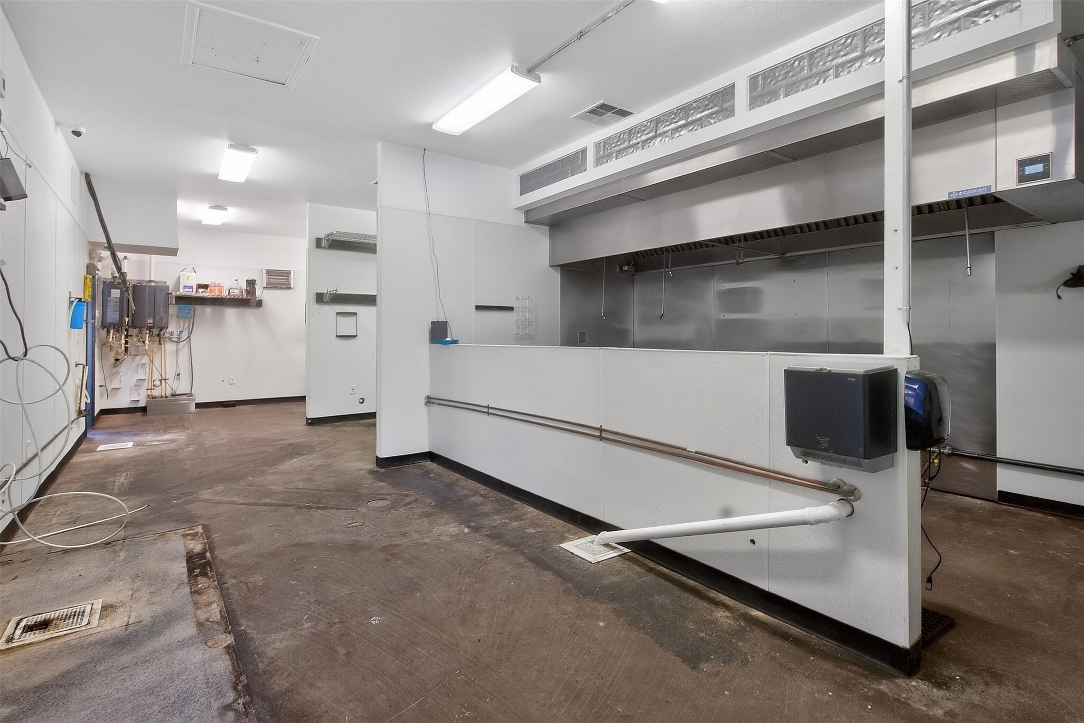 Commercial kitchen with a stainless-steel exhaust hood and long white service counter.