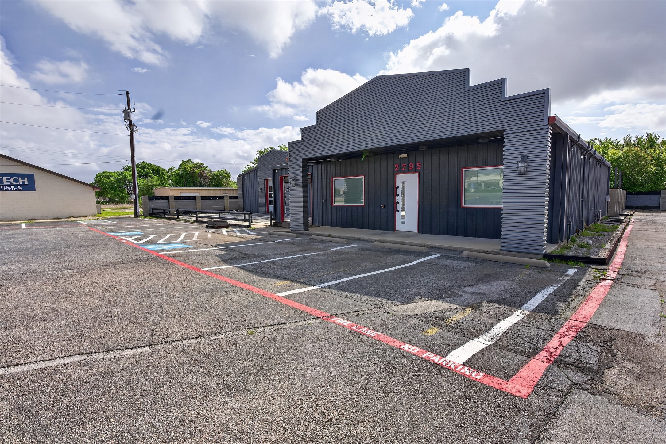 Commercial building with a stepped gray facade, red-trimmed windows, and parking spaces in front.