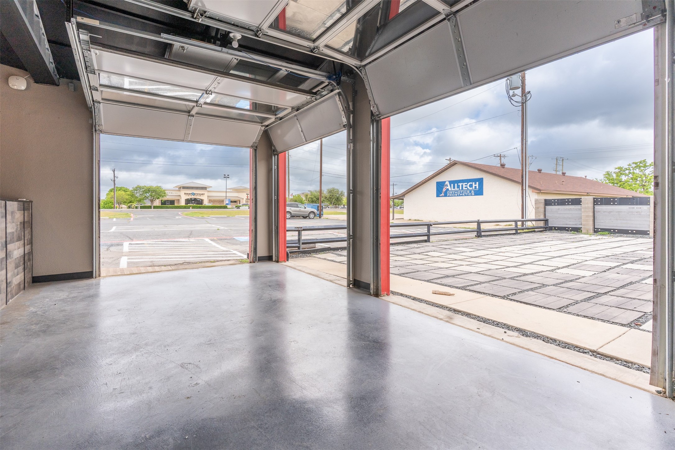Vacant commercial garage with raised overhead doors opening onto a paved outdoor area.