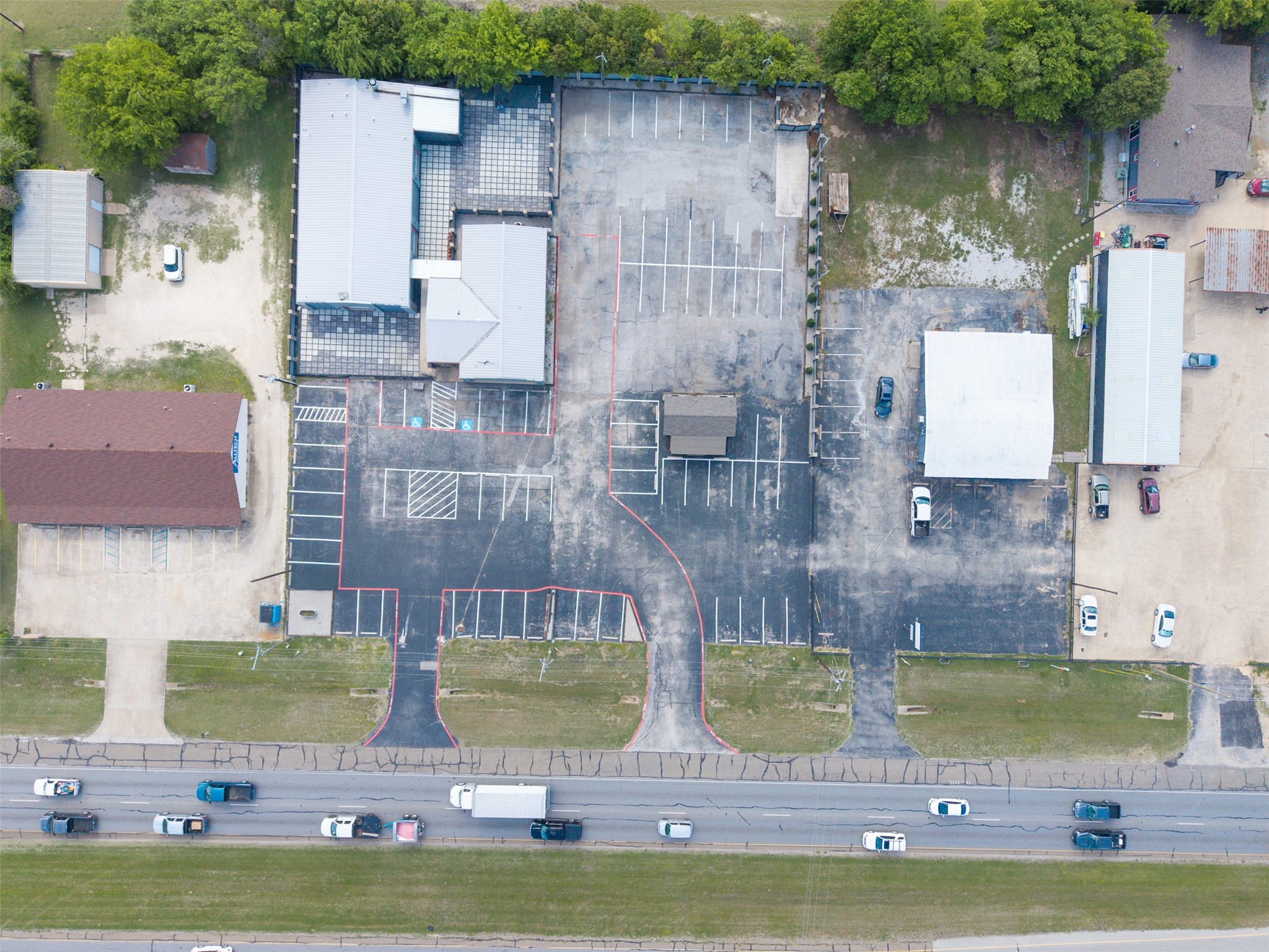 Aerial view of commercial buildings and parking lots beside a busy road.