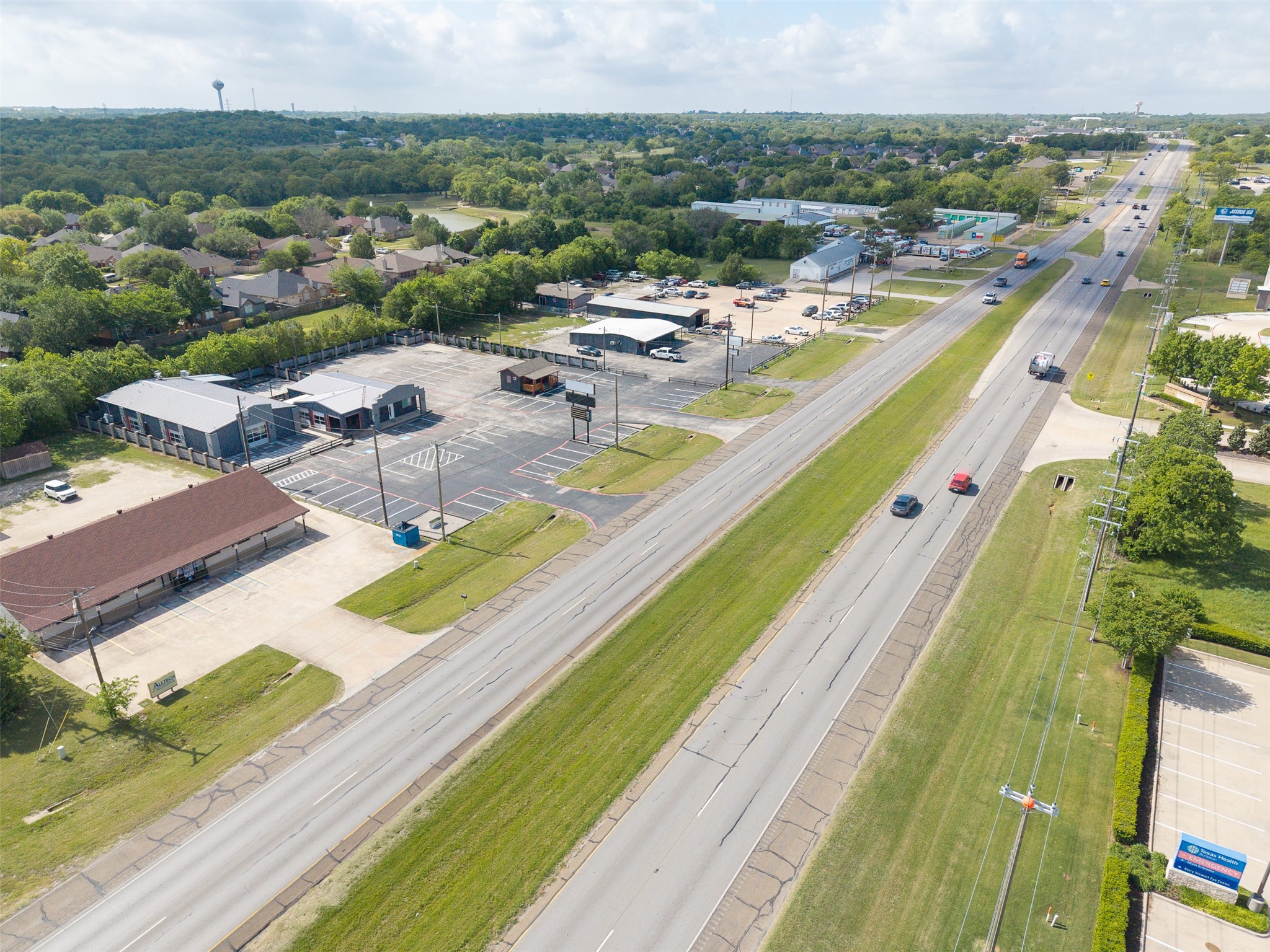 Aerial view of commercial buildings and parking lots along a divided boulevard.